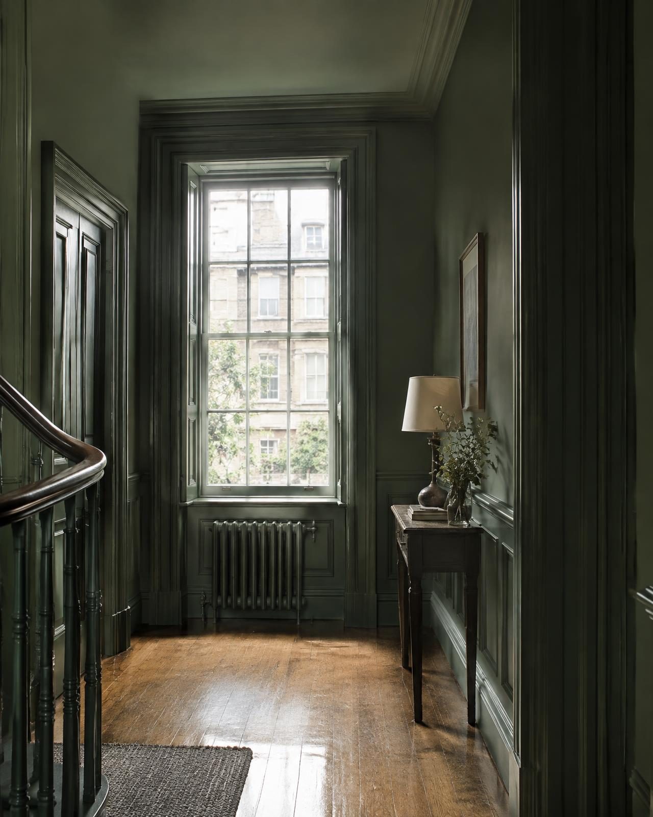A green-panelled townhouse landing with a tall sash window and oak floor